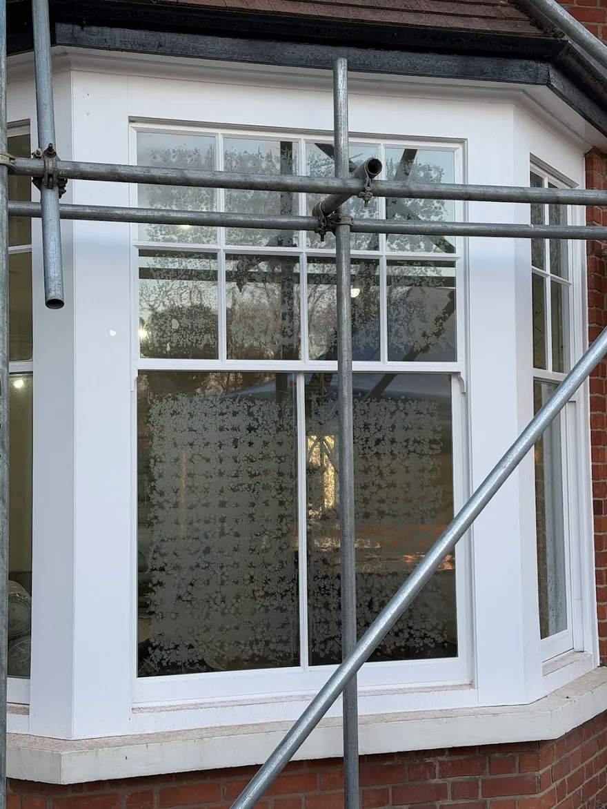 Morning dew forming a delicate frost-like pattern on the outside of vacuum glazing in a bay window — a sign the glass is insulating well