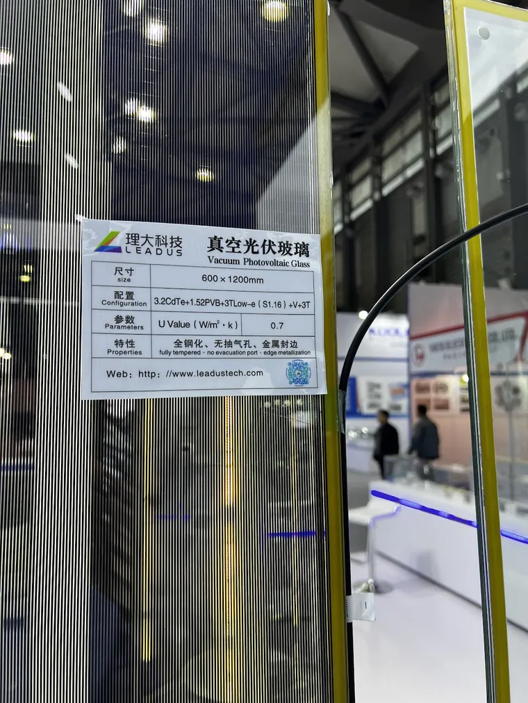 Spec label at a Chinese expo for vacuum photovoltaic glass — a vacuum unit with an integrated solar layer, listing a 0.7 W/m²K U-value