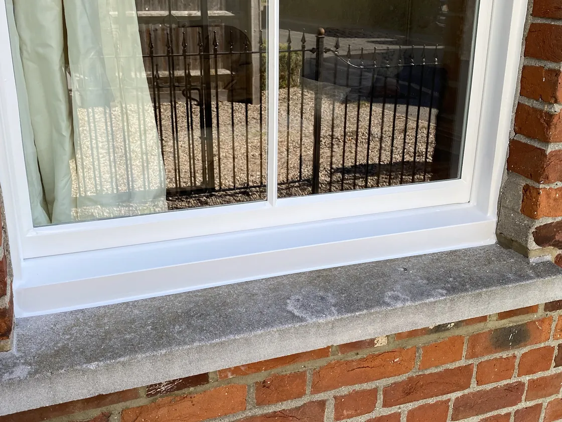 Close-up of vacuum insulated glazing fitted into a traditional white-painted timber sash window on a period brick house