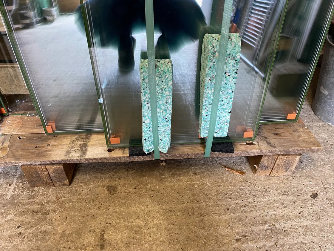 Vacuum insulated glazing units standing on a pallet, showing the two panes and the slim sealed vacuum edge along each unit