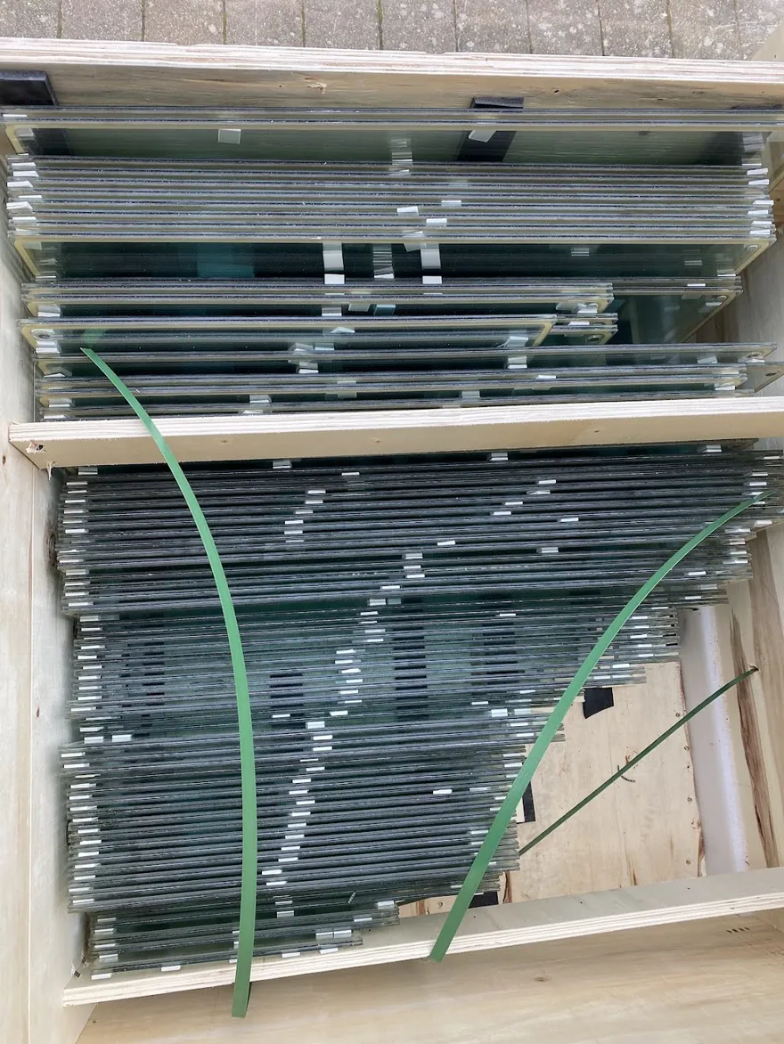 Vacuum insulated glazing units stacked edge-on in a timber shipping crate, ready for delivery